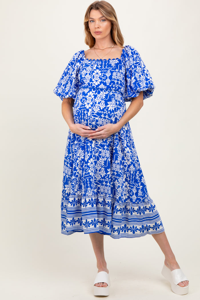 woman wearing a blue floral maternity dress with puff sleeves and a baby bump visible