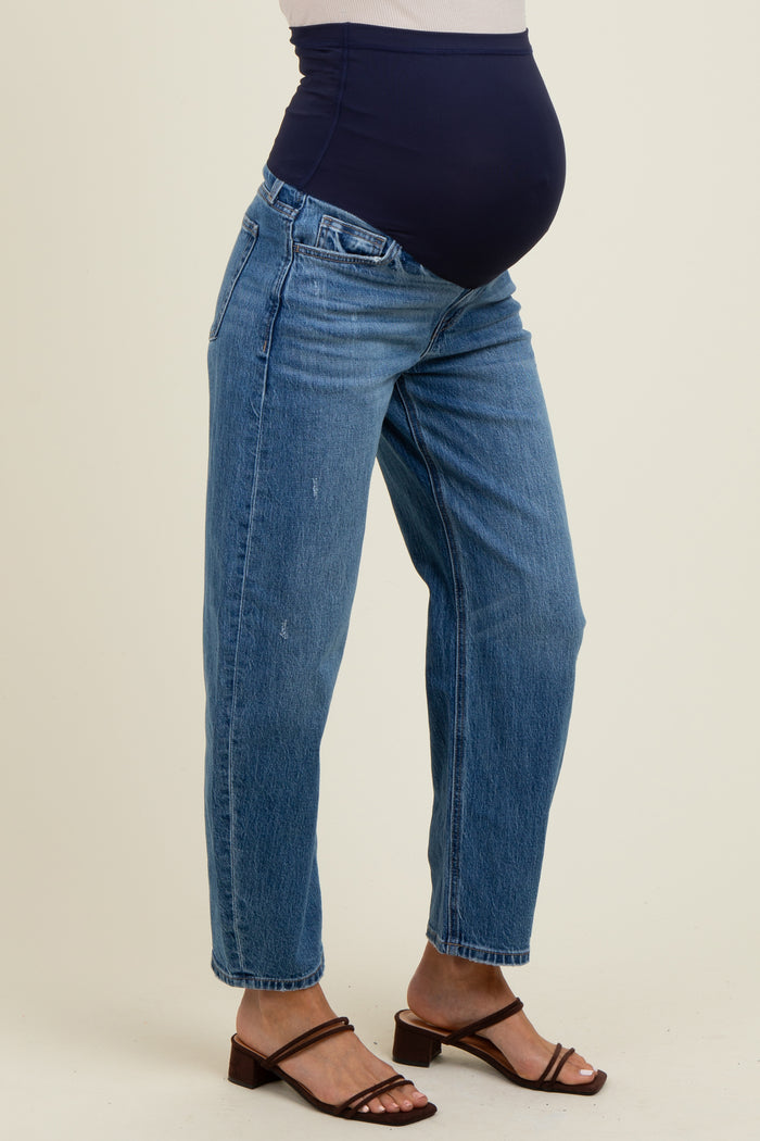 woman wearing light blue maternity jeans with a navy blue over-the-bump waistband and strappy sandals, baby bump visible