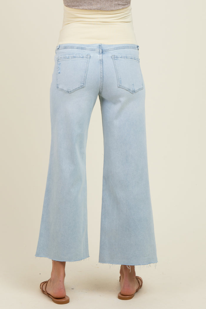 woman wearing light blue maternity wide leg jeans with a beige belly band visible at the waist