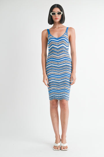 woman wearing a fitted blue and white zigzag patterned knit dress and oversized sunglasses