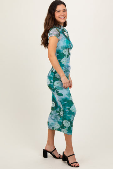 woman wearing a fitted green floral midi dress with short sleeves and a side slit