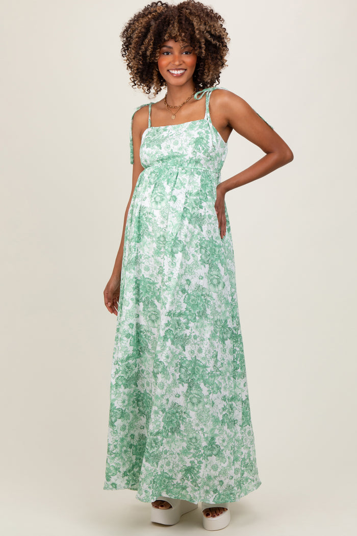 woman wearing a green floral maternity maxi dress with tie straps and a visible baby bump