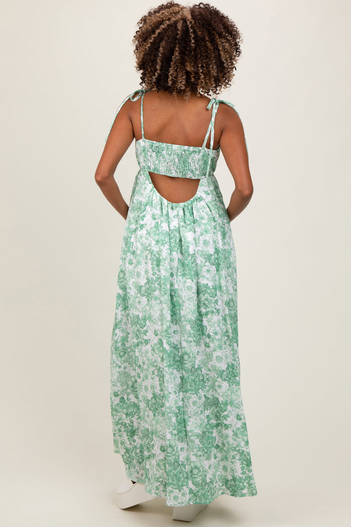 woman wearing a green floral maternity maxi dress with tie straps and an open back, showcasing her baby bump
