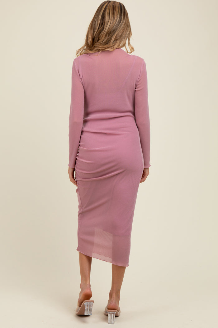 woman wearing a light pink long sleeve maternity dress with ruched detailing at the back and sheer fabric