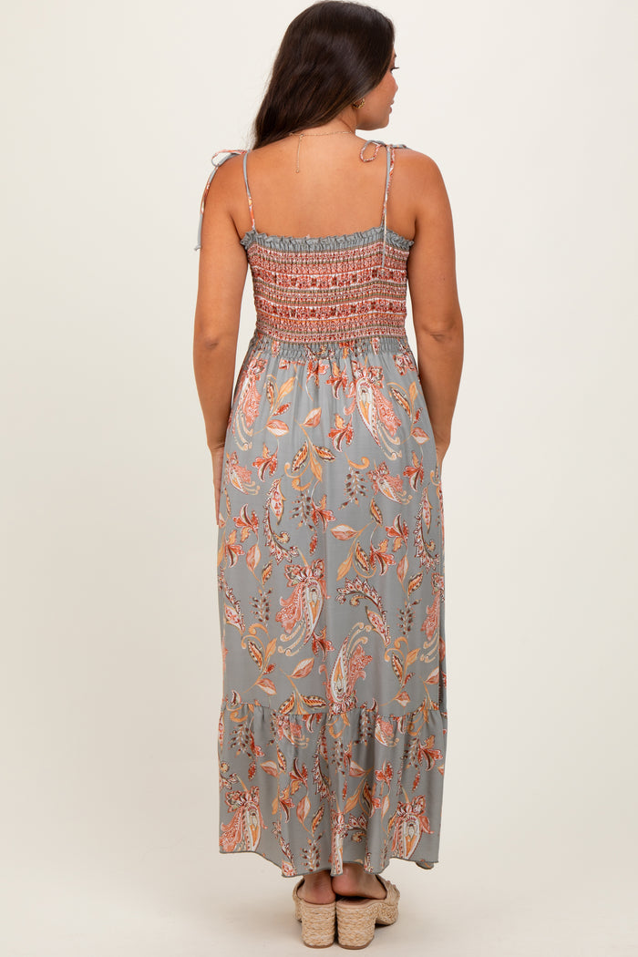 woman wearing a long floral maternity dress with tie straps and a smocked bodice, showing a flowy skirt from the back