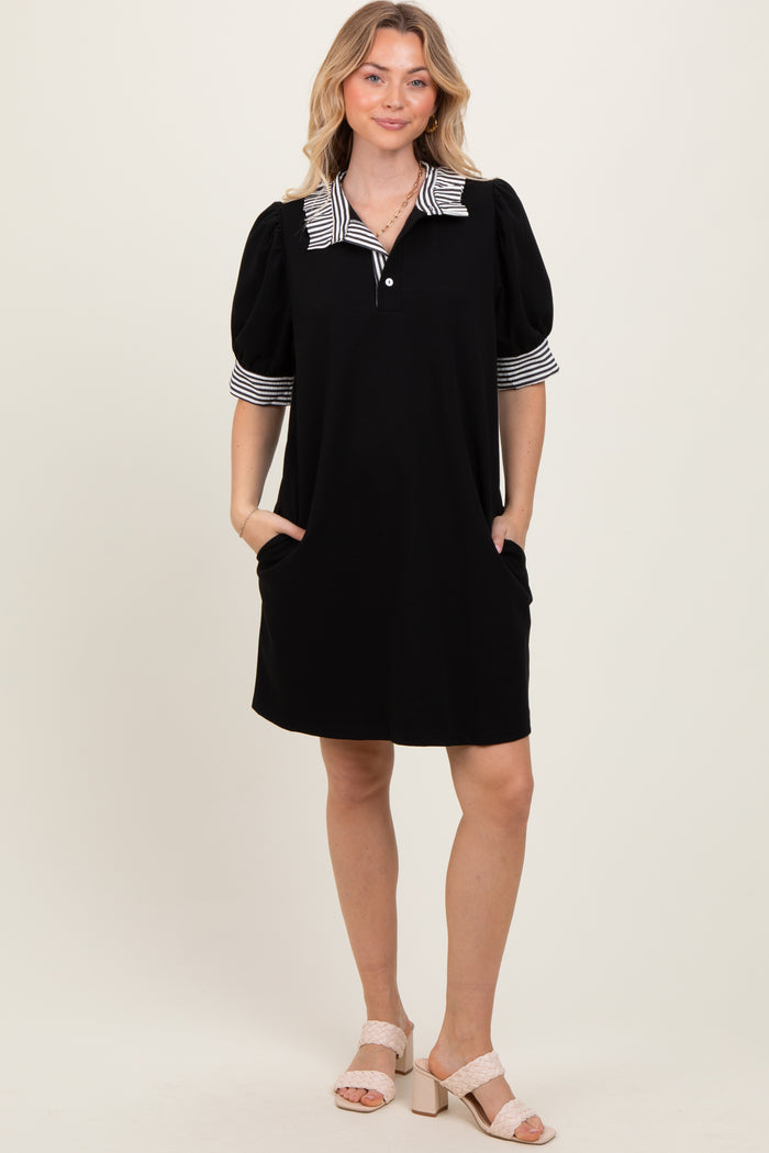 woman wearing a black short sleeve dress with a striped collar and puff sleeves, featuring side pockets