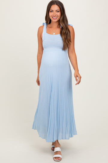 woman wearing a light blue maternity maxi dress with tie strap details and flowing pleats
