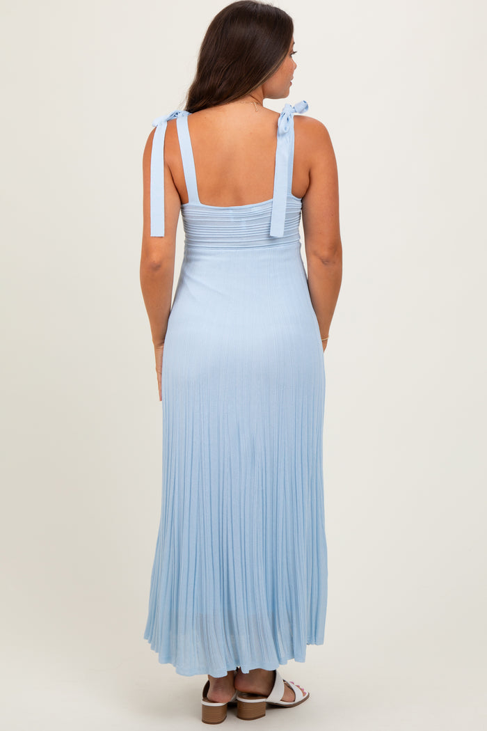 woman wearing a light blue maternity maxi dress with adjustable tie straps and a pleated skirt