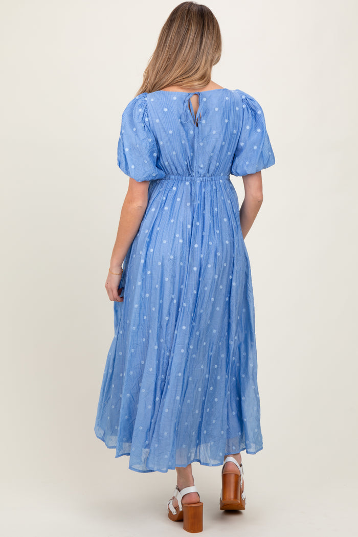 woman wearing a light blue maternity dress with puff sleeves and a back keyhole detail, featuring a flowy silhouette