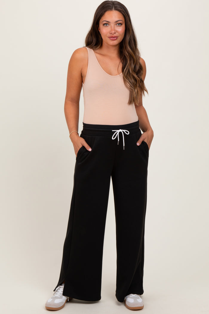 woman wearing a beige maternity bodysuit and black wide-leg maternity pants with pockets and drawstring detail