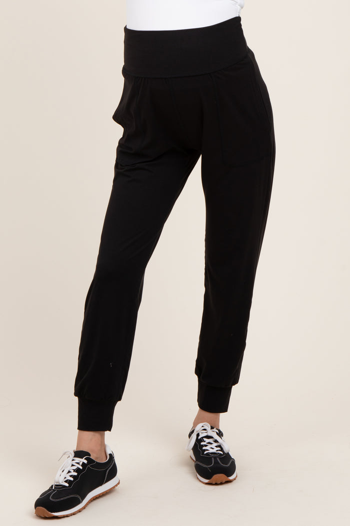 woman wearing black maternity joggers with a high waistband and side pockets, paired with sneakers