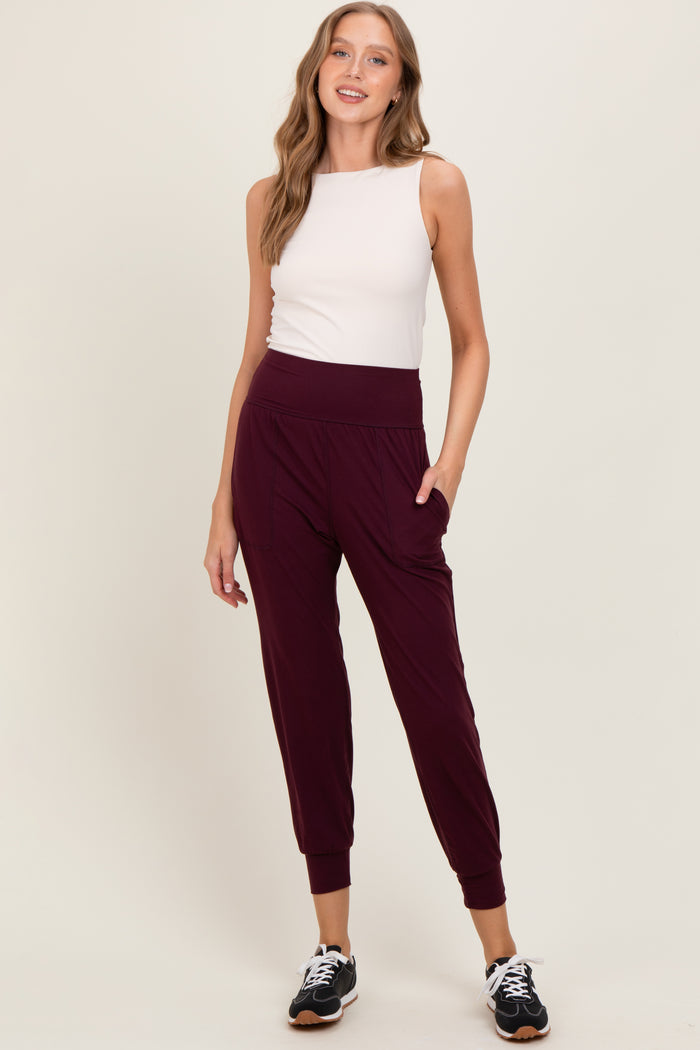 woman wearing a white sleeveless top and burgundy jogger pants with pockets