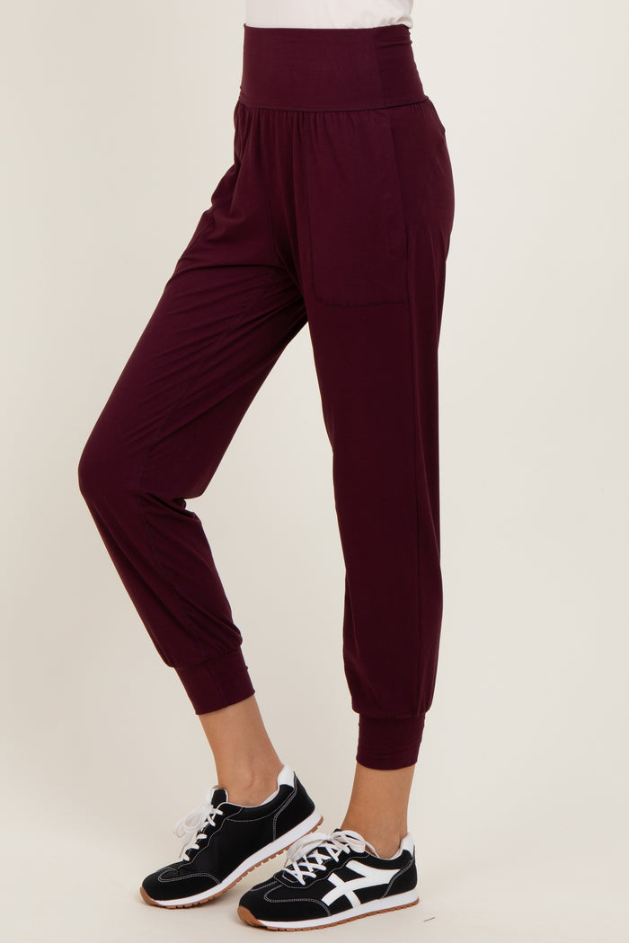 woman wearing burgundy relaxed fit jogger pants with side pockets and cuffed ankles, paired with black sneakers
