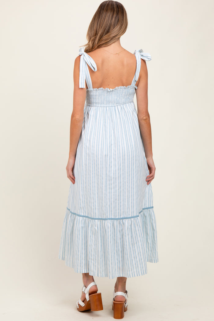 woman wearing a light blue striped maternity dress with tie straps and a ruffled hem, showing off her baby bump