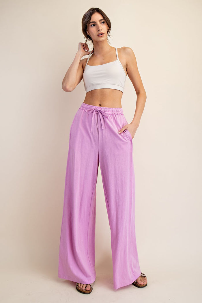 woman wearing a light gray cropped tank top and loose pink wide-leg pants with pockets