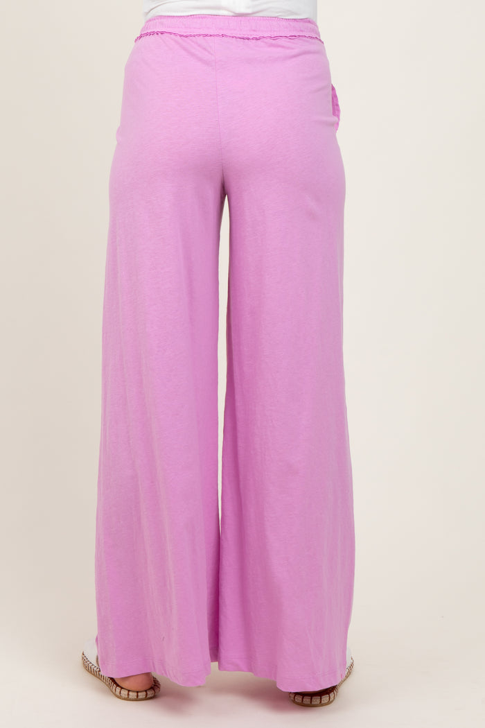 woman wearing pink wide-leg maternity pants, showing the back view of the garment