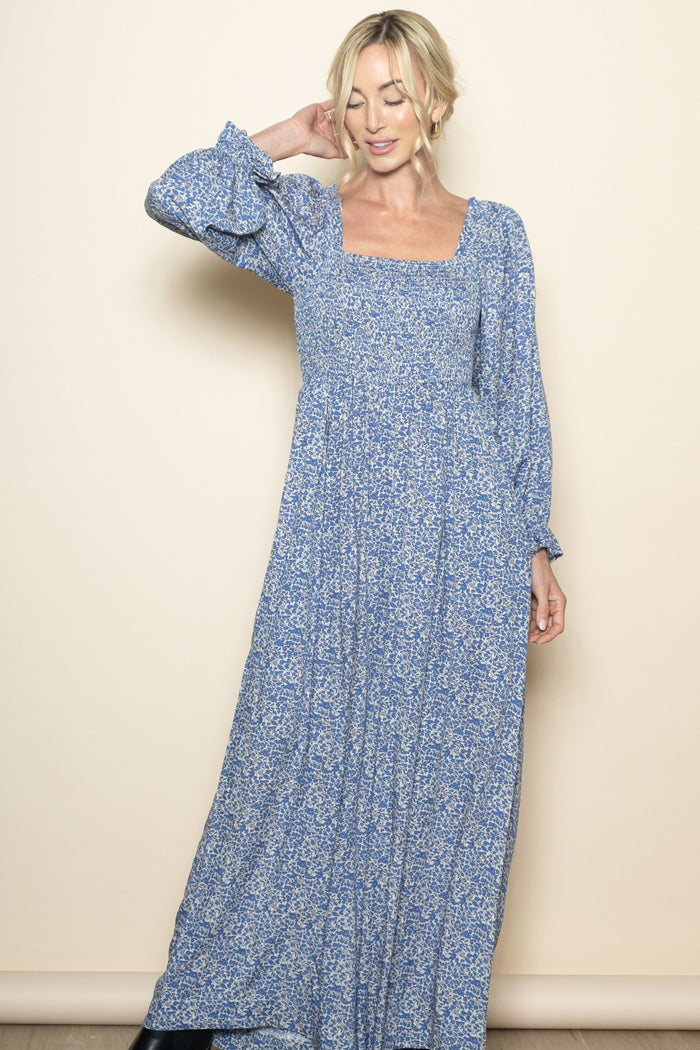 woman wearing a blue floral long sleeve maxi dress with a square neckline and flowy skirt
