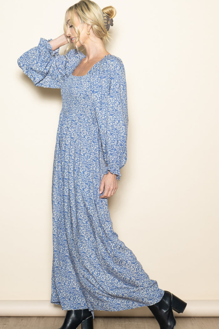 woman wearing a blue floral maxi dress with long sleeves and a square neckline, styled with black ankle boots