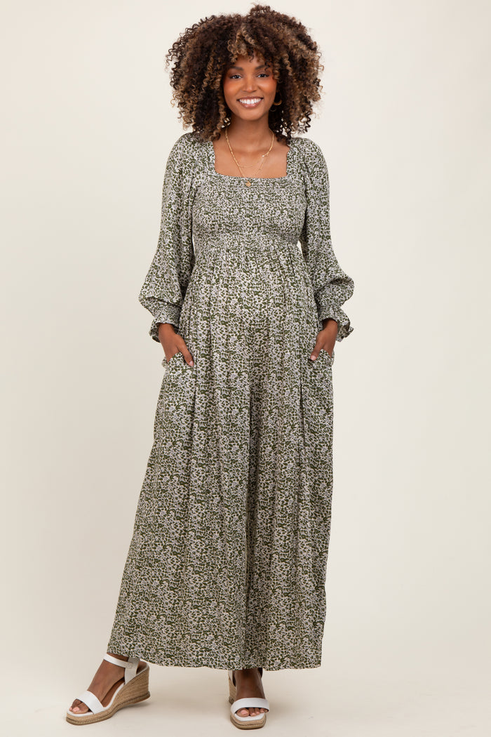 woman wearing a green floral maternity maxi dress with long sleeves and pockets, showing her baby bump