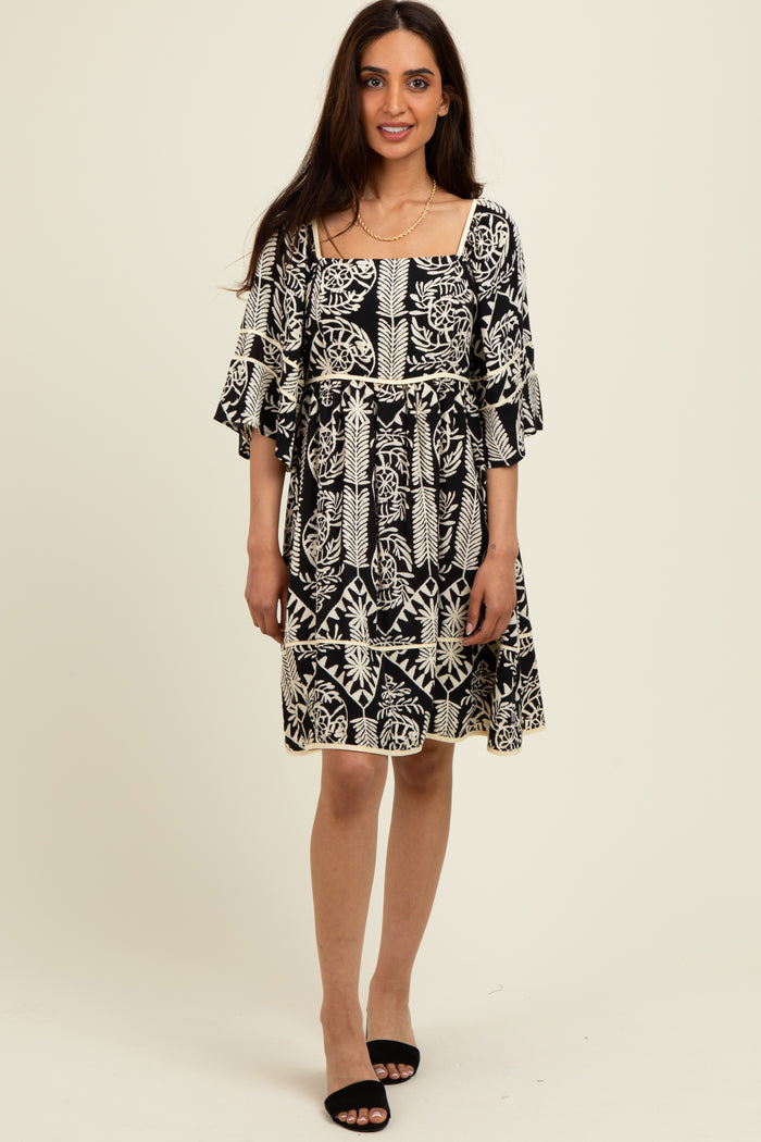 woman wearing a black and white patterned short dress with flutter sleeves and a square neckline