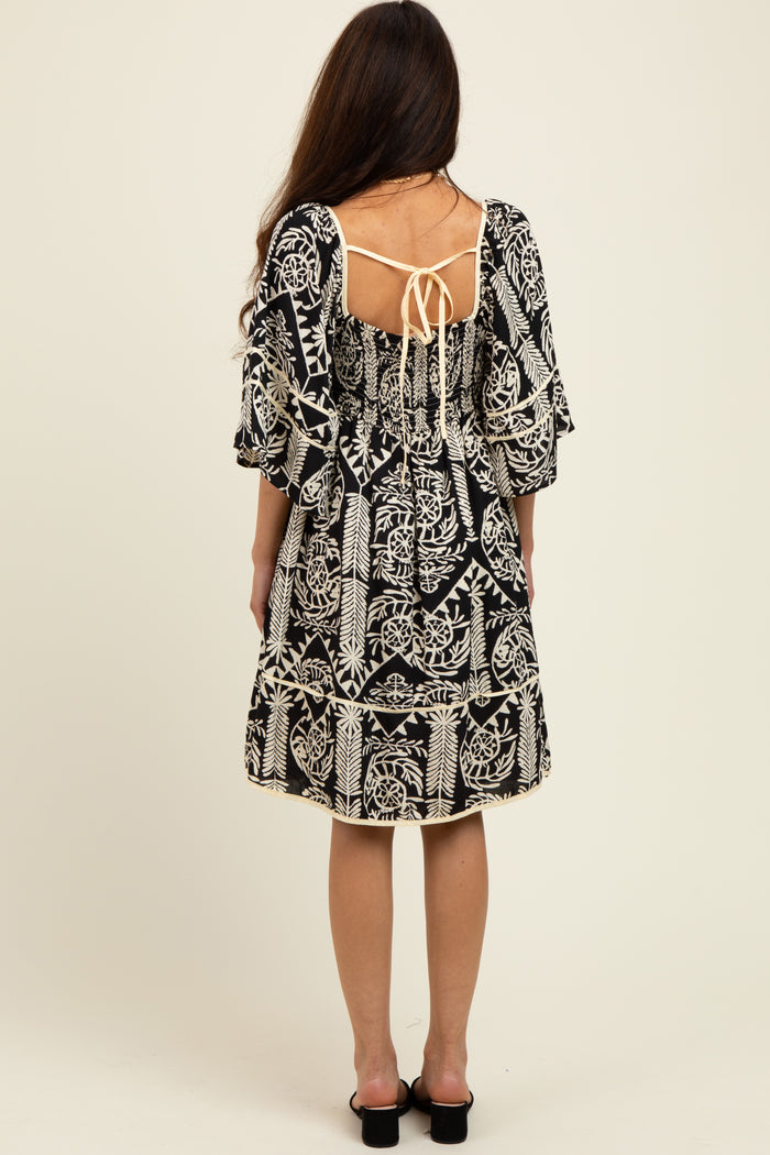 woman wearing a black and white patterned dress with flutter sleeves and back tie detail