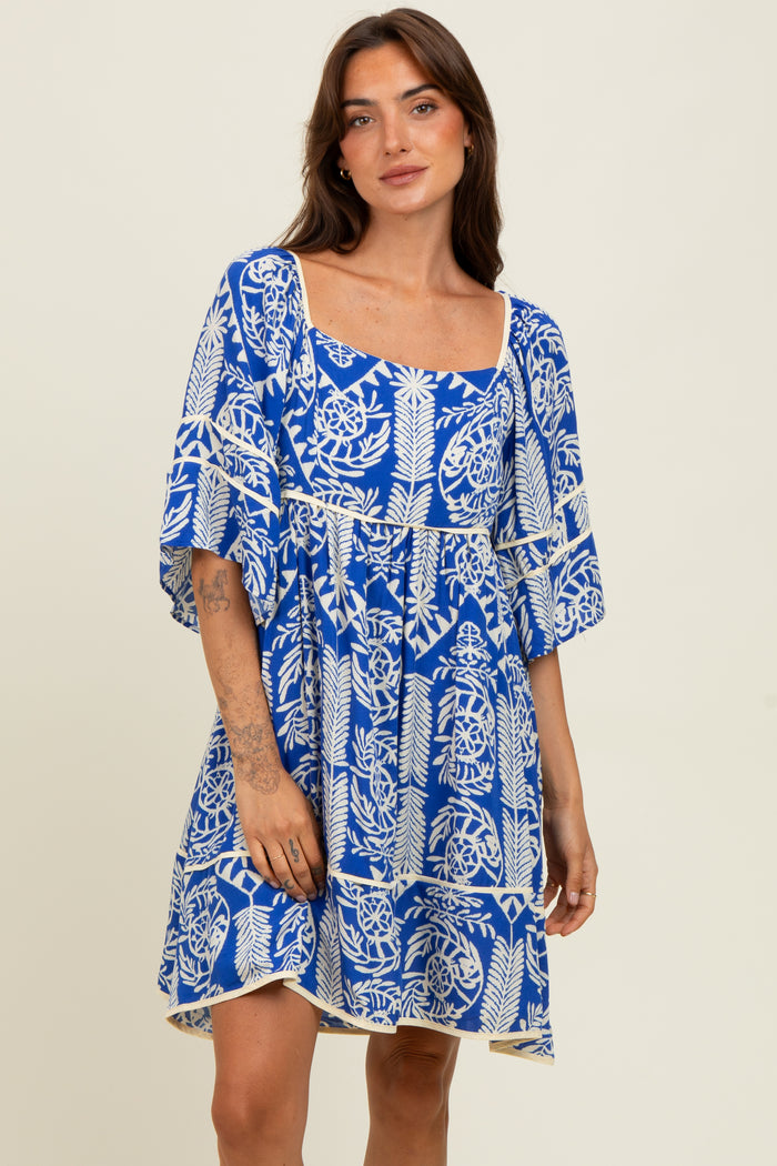 woman wearing a vibrant blue short sleeve dress with a floral print and a square neckline