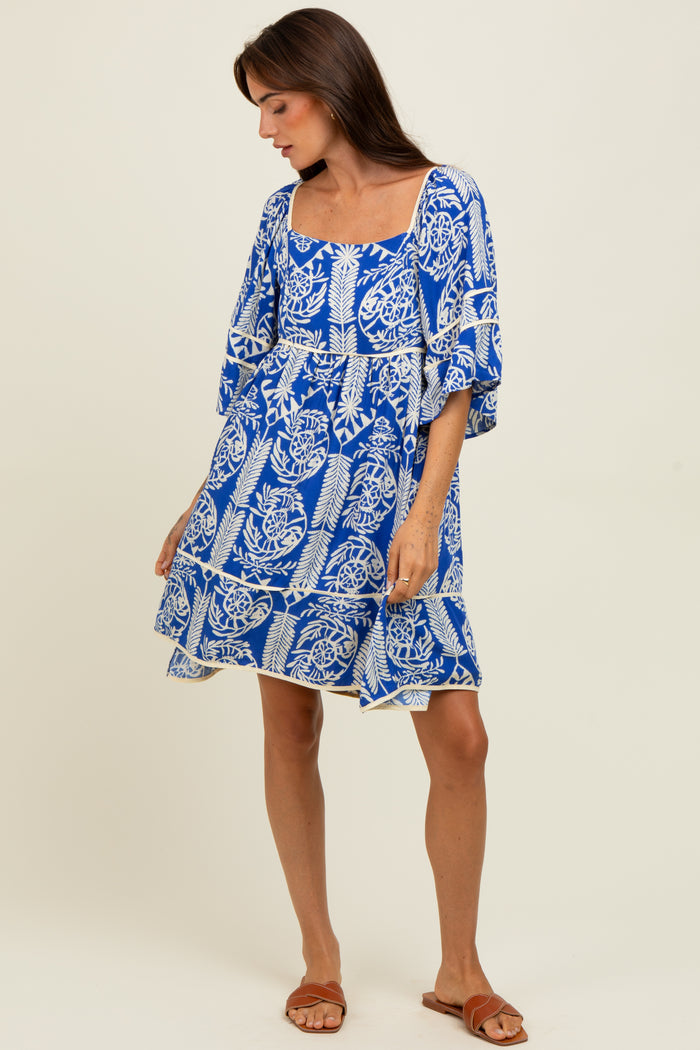 woman wearing a blue and white floral print short dress with puff sleeves and a tiered hemline