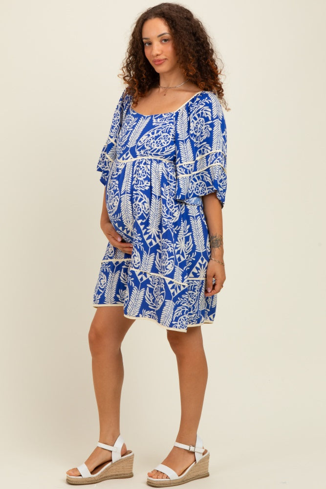woman wearing a blue and white patterned maternity dress with a baby bump, styled with white wedge sandals