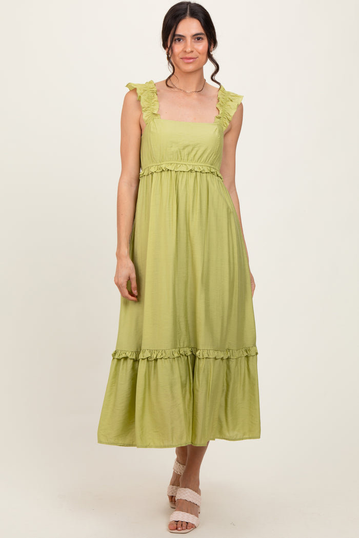 woman wearing a light green maxi dress with ruffled straps and a tiered skirt
