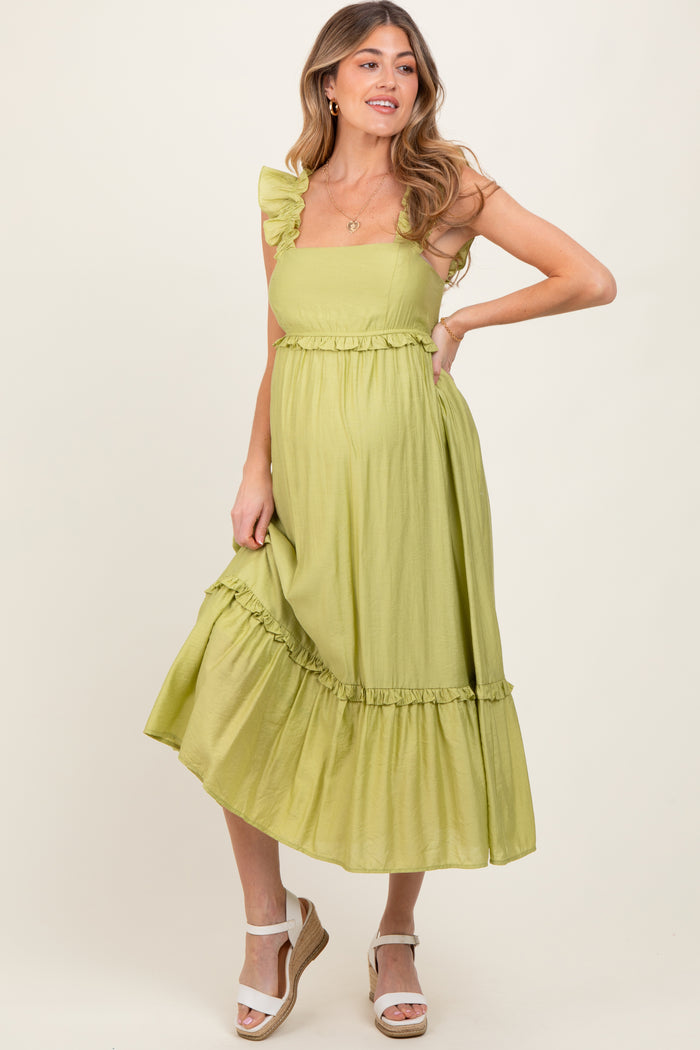 woman wearing a light green maternity dress with ruffle straps and a tiered skirt, showing a baby bump