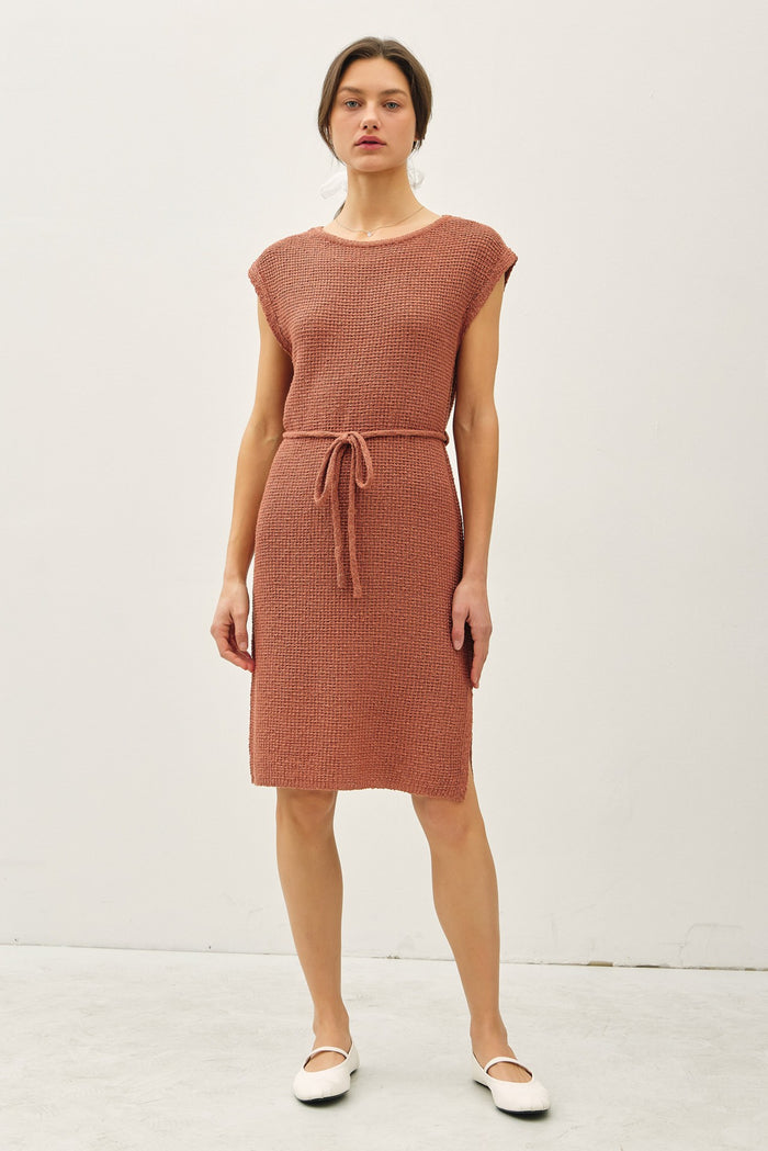 woman wearing a rust-colored knit dress with short sleeves and a tie waist detail