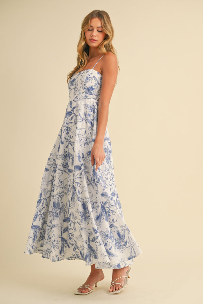 woman wearing a white floral print maxi dress with adjustable straps and a flowing skirt
