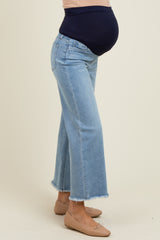 woman wearing light blue maternity jeans with a frayed hem and a visible baby bump