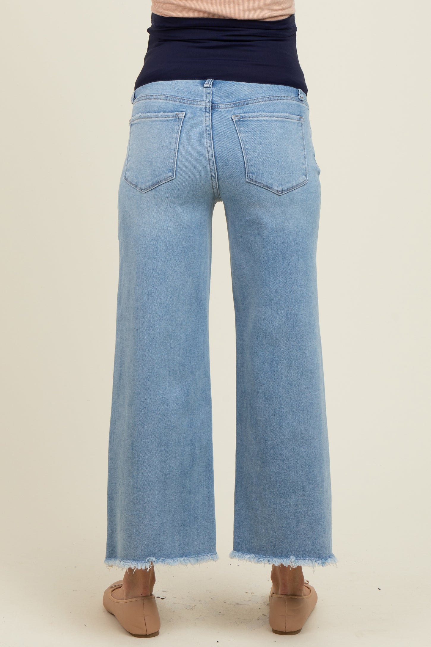 woman wearing light blue maternity wide-leg jeans with frayed hem, showing the back view