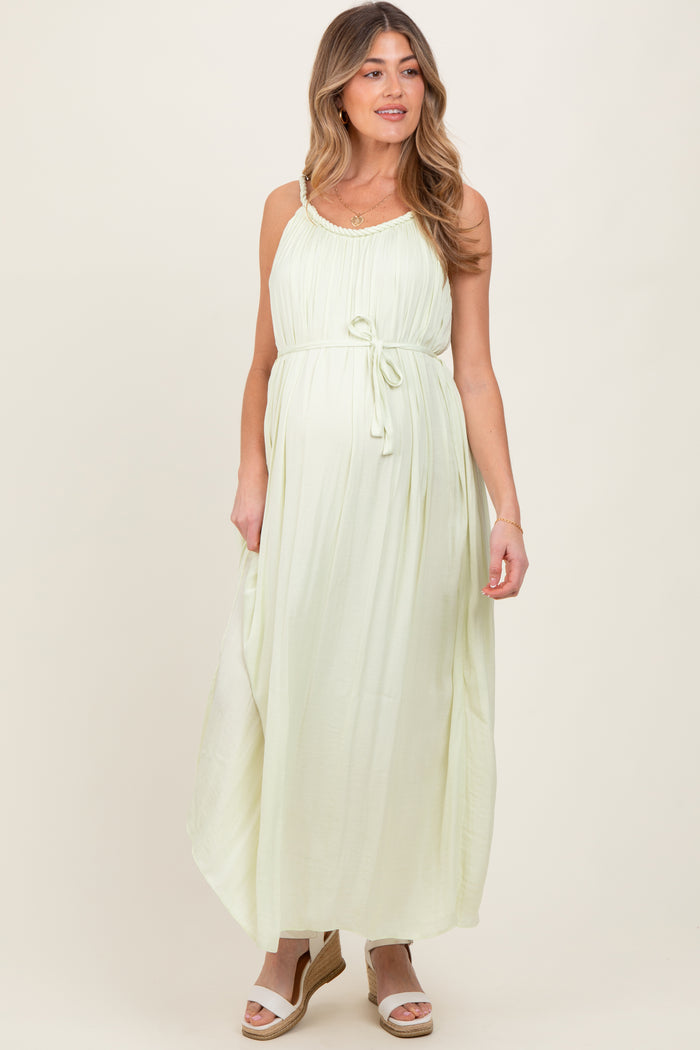 woman wearing a light green maternity maxi dress with a tie waist and adjustable straps, showing a baby bump