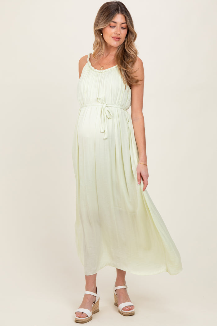 woman wearing a light green maternity maxi dress with a tie waist and a visible baby bump