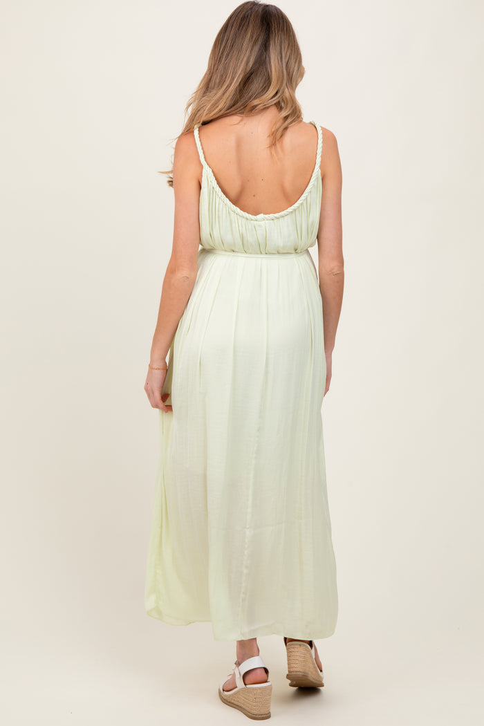 woman wearing a light green maternity maxi dress, showcasing a back view with adjustable straps and a flowy silhouette