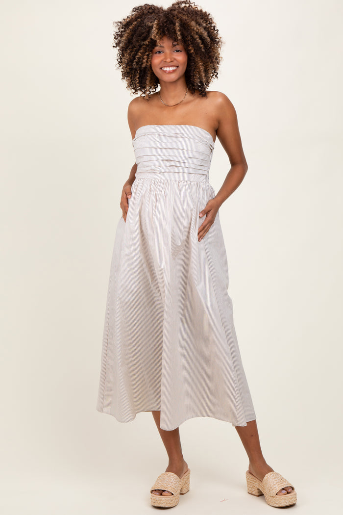 woman wearing a striped strapless maternity dress with a fitted bodice and flowy skirt, showing her baby bump