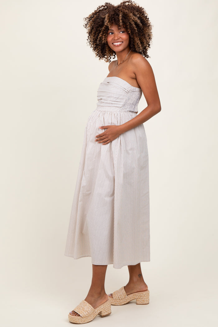 woman wearing a striped strapless maternity dress and holding her baby bump