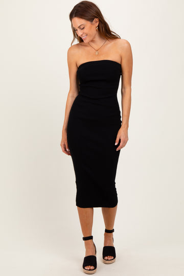 woman wearing a black strapless midi dress with a fitted silhouette and high slit, standing and smiling