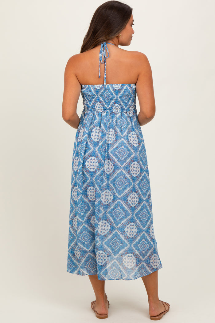 woman wearing a blue patterned maternity maxi dress with a halter neckline and a flowy silhouette