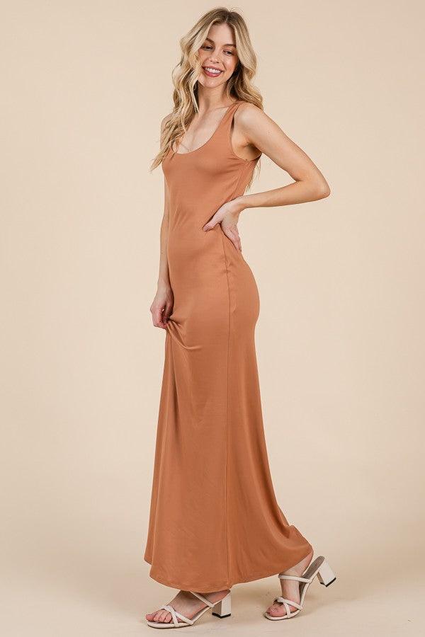 woman wearing a rust-colored sleeveless maxi dress with a fitted silhouette and strappy white heels
