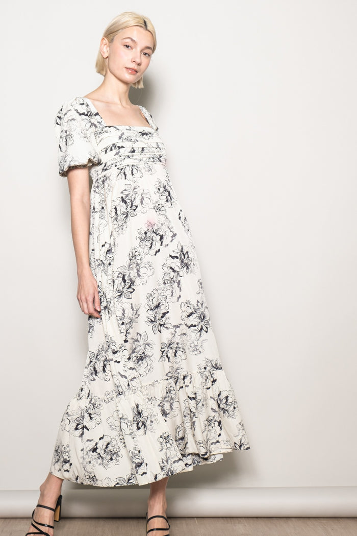 woman wearing a cream floral maxi dress with puff sleeves and a tiered skirt