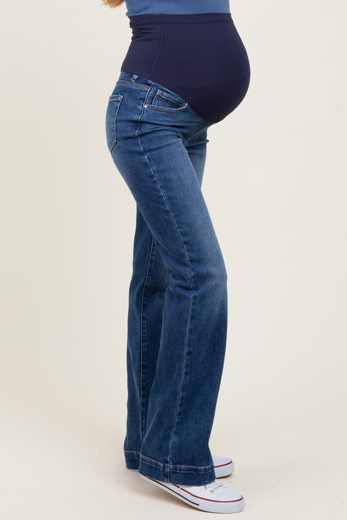 woman wearing dark blue maternity flared jeans with a supportive belly panel displaying her baby bump