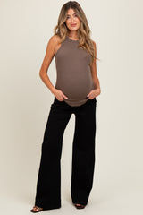 woman wearing a brown maternity tank top and black wide-leg pants, showing her baby bump