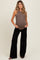 woman wearing a brown maternity tank top and black wide-leg pants, showing her baby bump