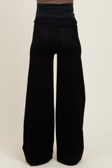 woman wearing black wide-leg maternity pants, seen from the back, with a fitted top above