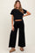 woman wearing a black cropped t-shirt and black wide-leg maternity pants