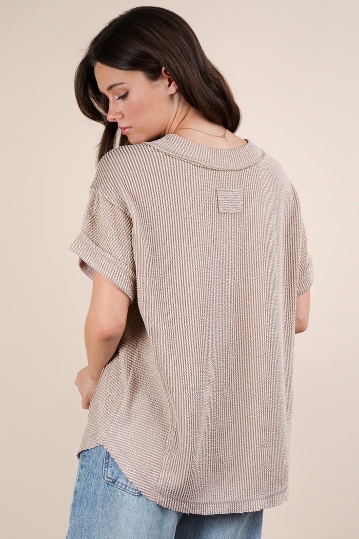 woman wearing a taupe oversized knit sweater with rolled sleeves and a round neckline, shown from the back