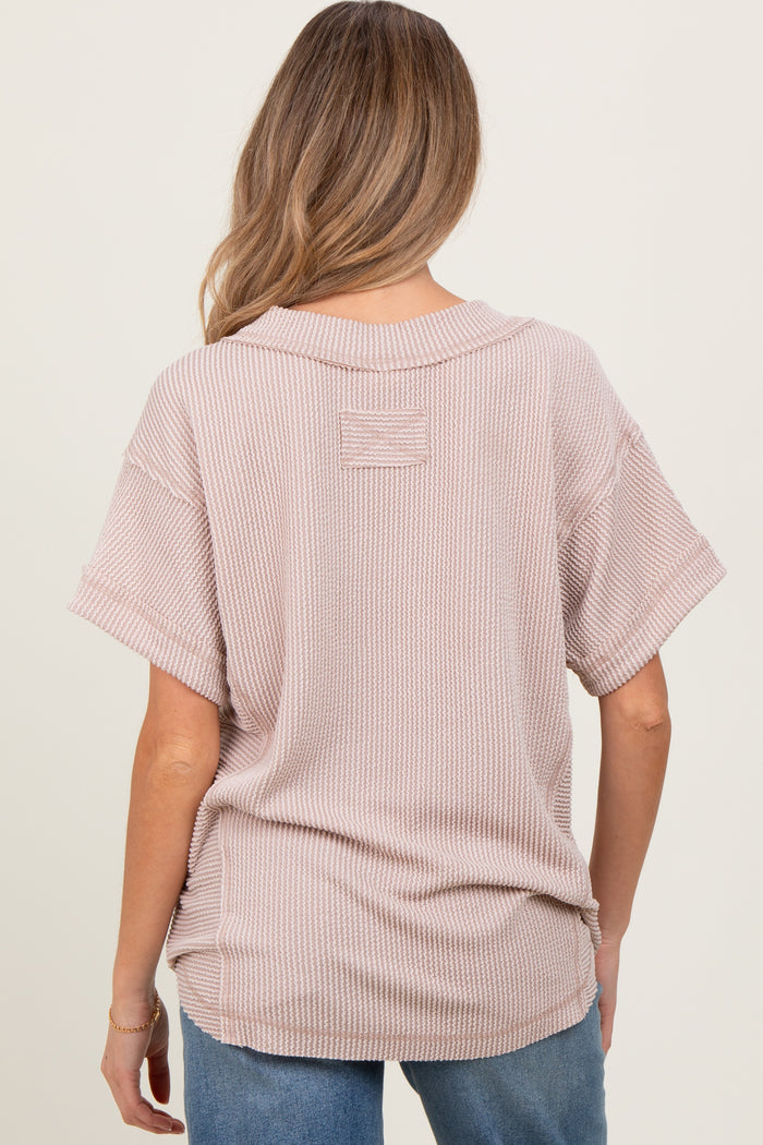 woman wearing a light pink oversized maternity top with a textured pattern, seen from the back